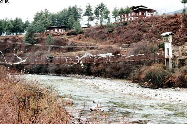 Prayer flags hang from a rope bridge in Paro on trail climbing to Takstang. Bhutan.