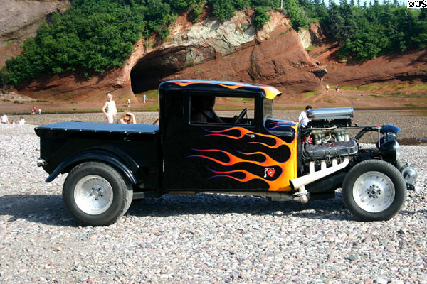Flame-painted pickup hotrod at car rally on beach. NB.