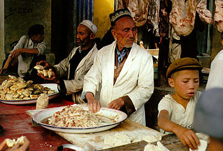 Family sells prepared foods at Sunday market in Kashgar. China.