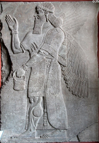 One of pair of Assyrian reliefs (883-859 BCE) of libation induced transition between winged human body with bird head to more normal form with panel over inscribed with cuneiform text at Pergamon Museum. Berlin, Germany.