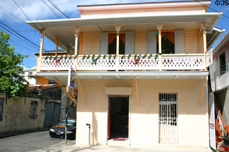 Pink building with cantilevered balcony overhanging sidewalk. Roseau, Dominica.