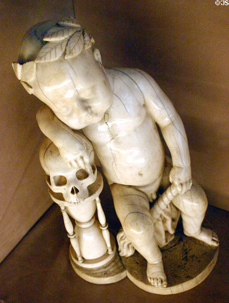 Ivory sleeping infant crowned with laurel wreath leaning on skull & hourglass symbolic of Vanity (17thC) from Germany at Louvre Museum. Paris, France.