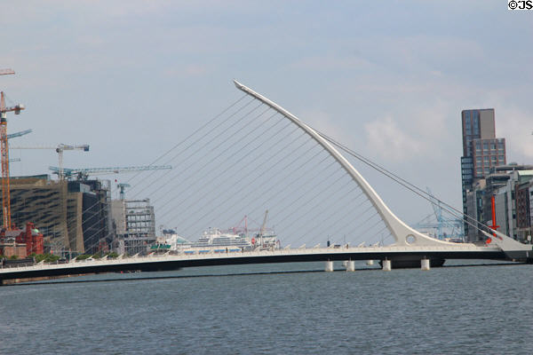 Samuel Beckett Bridge shaped like Irish harp over River Liffey with cruise ship in distance. Dublin, Ireland.