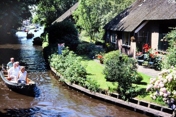 Canal cruising behind houses. Giethoorn, Netherlands.
