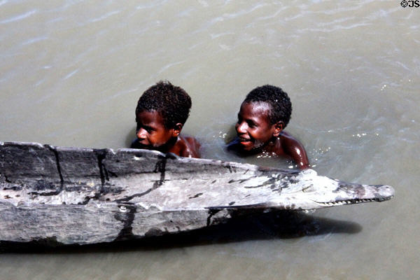 Children swimming in the water near a canoe in Tambanam. Papua New Guinea.
