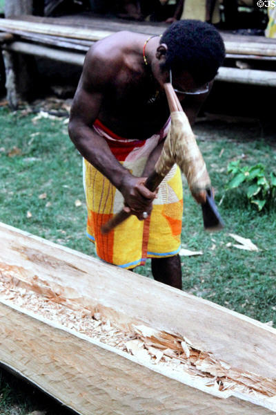 Canoe carver using a traditional handle with metal blade, Timbunke. Papua New Guinea.