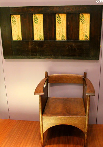 Argyle Street Tearoom oak armchair (1898-9) by Charles Rennie Mackintosh & stained glass door panel by George Walton & Co. at Kelvingrove Art Gallery. Glasgow, Scotland.