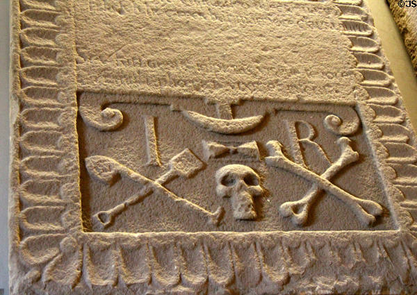 Tombstone with skull & crossbones & crossed shovels with initials IR for James Rex in museum at St Andrews Cathedral. St Andrews, Scotland.