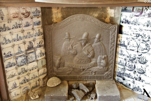 Delftware tiles surrounding fireplace with cast iron fire back at Chastleton House. Moreton-in-Marsh, England.