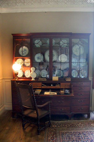 Wide secretary desk & spool framed wicker chair surmounted by glass display cabinet at Chastleton House. Moreton-in-Marsh, England.