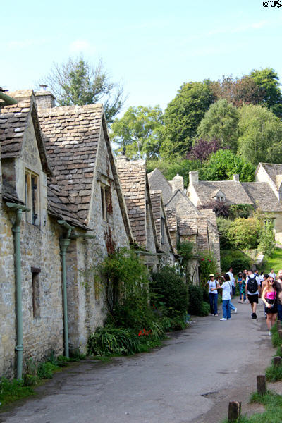 Row of weavers' cottages with larger homes in background. Bibury, England.