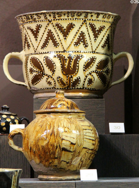 Slipware posset pot with tulips inscribed "The best is not too good for you // Robbort Wood" (1670-75) over honey pot (1680-1700) both made in North Straffordshire at Potteries Museum & Art Gallery. Hanley, Stoke-on-Trent, England.