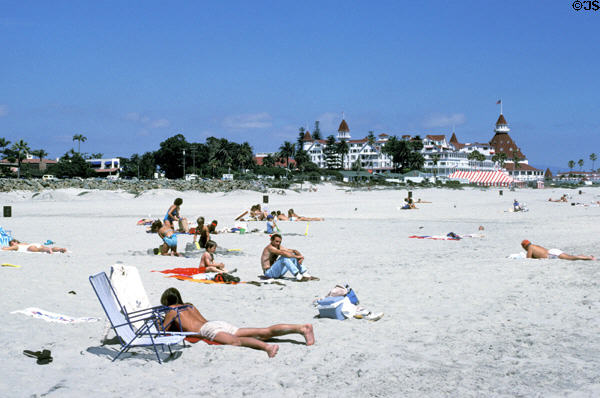 Sun bathers on beach of Hotel del Coronado. San Diego, CA.