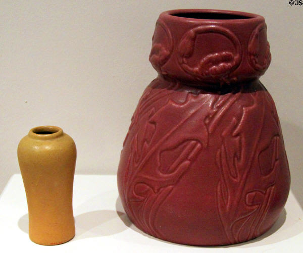 Red pottery vase with flowers & leaves (1903) by Artus Van Briggle beside unknown vase (1905) at Colorado Springs Fine Arts Center. Colorado Springs, CO.