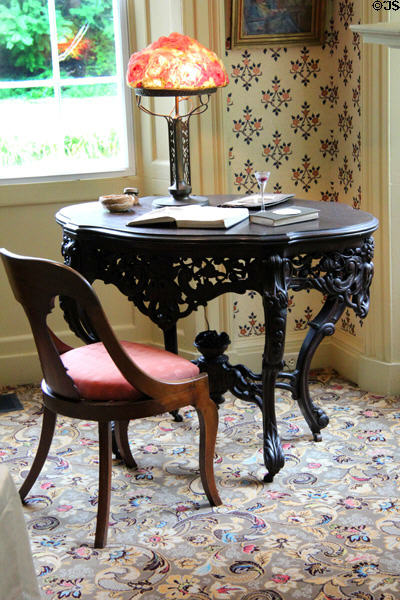 Elaborate round table with Art Nouveau lamp in Art Colony bedroom at Florence Griswold Museum. Old Lyme, CT.