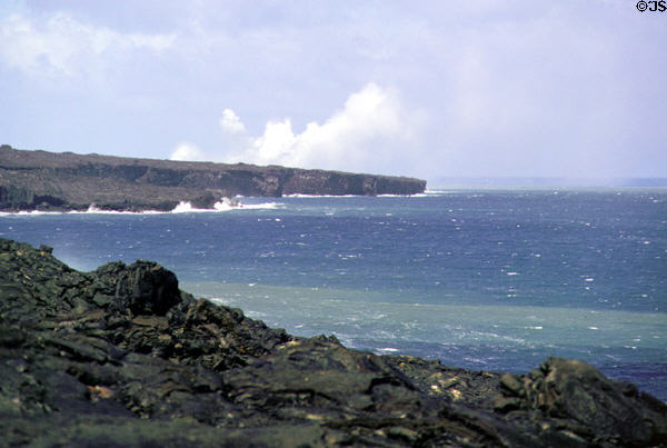 Steam rises as lava flows into sea in Volcanoes National Park. Big Island of Hawaii, HI.