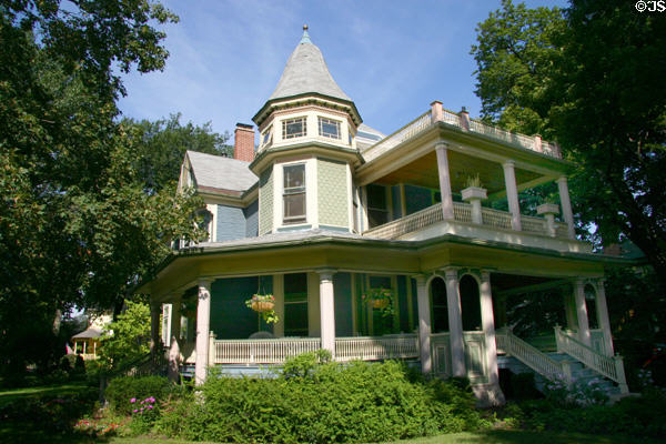 Green & blue Queen Anne house with wrap around porch at corner of North Forest & Superior. Oak Park, IL.