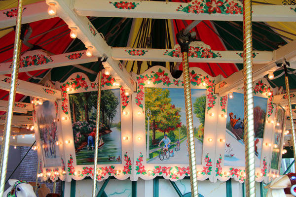 Painted scenes of children at play on Elaine Wilson Carousel at The Strong National Museum of Play. Rochester, NY.
