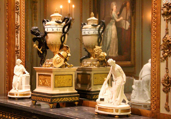 French mantle clock with Eros & snake handles around horizontal number rings (c1775-80) by Jean-Baptiste Lepaute & Pierre Henry flanked by porcelain figures of war & peace (c1780s) by Dihl & Guérhard of Paris at Metropolitan Museum of Art. New York, NY.