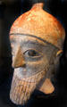 Terra-cotta head of male statue with conical helmet painted red & black from Nicosia, Cyprus at Neues Museum. Berlin, Germany.