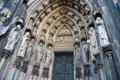 Carved figures beside south entrance door with crucifixion of Peter to Köln Cathedral. Köln, Germany.