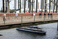 Love locks attached to Hohenzollern Bridge with passenger train crossing and tour boat passing underneath. Köln, Germany.