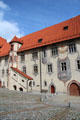 Courtyard & building with covered external staircase, red tiled peaked roof and many painted decorative elements at Hohes Schloss zu Füssen. Füssen, Germany.