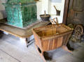 Rocking cradle & other local carvings beside tiled heating stove at Oberammergau Museum. Oberammergau, Germany.