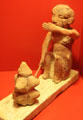 Egyptian sculpture depicting woman baking bread by placing dough in heated clay mold on glowing charcoal at Museum of Bread and Art. Ulm, Germany.