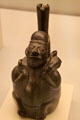 Chimu culture ceramic stirrup-spout bottle with person with dog on shoulders from Peru at Museum of America. Madrid, Spain.