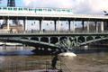 Metro train crosses upper level of Pont de Bir-Hakeim pedestrian bridge near Eiffel Tower. Paris, France.