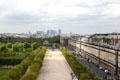 Tuileries gardens bordered by rue de Rivoli with highrises of La Defense beyond seen from Louvre Palace. Paris, France.