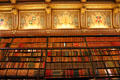 Decorative emblems bridging space between book shelves & ceiling in library at Château de Chantilly. Chantilly, France.