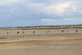 Visitors exploring tidal flats near city wall. Mont-St-Michel, France.