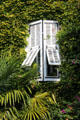Greenery covered building with wooden shutters covering narrow windows. St Paul de Vence, France.
