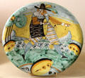 Ceramic deep plate painted with man playing drum at Musées des Arts Décoratifs. Lyon, France.