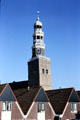 A church tower spires up behind identical houses. Hindeloopen, Netherlands.