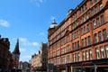 Red sandstone former City Improvement Trust. Block with octagonal corner tower with Tron Steeple beyond. Glasgow, Scotland.