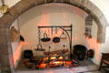 Kitchen fireplace with various metalware cookery items including flat bannock bread pans hanging from andiron at Crathes Castle. Crathes, Scotland.