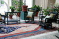 Wicker rocking chairs & table with potted plants commonly used in the early 20th C in conservatory at Eastman House. Rochester, NY.