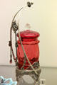 Blown glass pickle jar on silver plated stand with tongs by James W. Tufts Co., Boston, MA at Dallas Museum of Art. Dallas, TX.