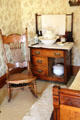 Rocking chair beside washstand with pitcher & basin plus chamber pot in farm house at Billings Farm & Museum. Woodstock, VT.