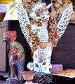 Winged carving stands over offering of rice cakes. Bali, Indonesia.
