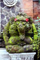 Moss covered elephant carving with flower offerings behind ears. Bali, Indonesia.